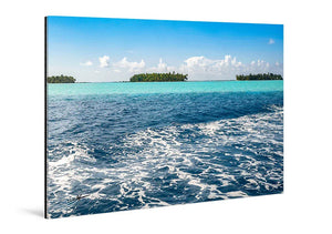 Tableau mural représentant un lagon turquoise avec écume au premier plan, îlots de palmiers à l’horizon et ciel bleu parsemé de nuages