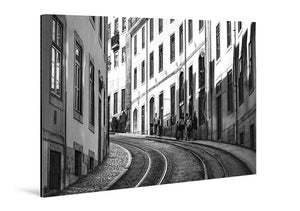 Tableau mural noir et blanc représentant une rue pavée de Lisbonne avec rails de tramway, façades anciennes et passants