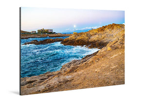 Tableau mural représentant une côte rocheuse au bord de la mer, avec vagues bleues, lumière dorée sur les rochers et horizon lumineuxt