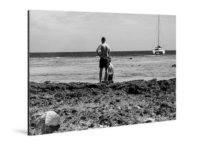 Tableau mural noir et blanc représentant un homme face à la mer, un voilier à l’horizon et un littoral rocheux au premier plan