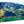 Glossy acrylic photo print featuring a vibrant mountain landscape with green hills and water.