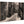 Black and white print of a narrow city street with tram tracks and pedestrians on wood panel
