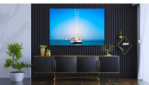 Tableau mural représentant un voilier face à l’horizon sur une mer bleu intense, avec d’autres bateaux au loin sous un ciel lumineux