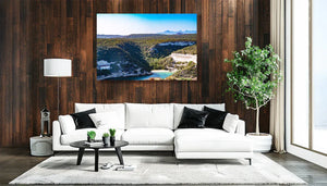 Modern living room with white sofa, wood panel wall, landscape art print, and indoor plant