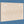 Rectangular light wood panel with two round cutout handles, plain blue background