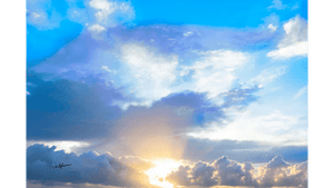 Golden sunrise rays emerging through dramatic clouds in a vibrant blue sky