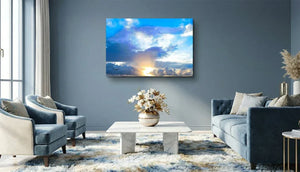 Tableau mural représentant la lumière du soleil traversant de grands nuages sous un ciel bleu, avec des rayons lumineux à l’horizon