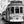 Black and white street photo of vintage tram in a European city with pedestrians nearby.