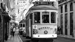 Black and white street photo of vintage tram in a European city with pedestrians nearby.