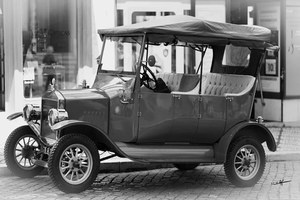 Monochrome photo of a classic vintage car parked on a cobblestone street