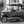 Monochrome photo of a vintage classic car with soft top parked on city street