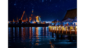 Night harbor scene with illuminated dock restaurant, city lights, cranes, and starry sky