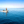 Three people on a small aluminum boat crossing calm blue ocean under clear sky