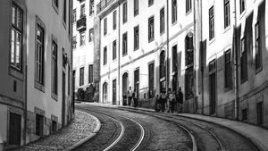 Black and white photo of curved streetcar tracks in a European city with people walking
