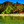 Tropical beach huts with palm trees and clear water, mountain backdrop, sunny day