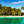 Tropical beach with palm trees, turquoise water, and bungalows under blue sky